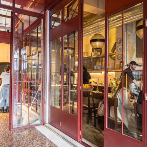 Εξωτερική όψη του καταστήματος ΜΑΝΑΡΙ με χαρακτηριστική μεταλλική πρόσοψη, όπου διακρίνονται custom διακοσμητικά στοιχεία και πτυσσόμενες μεταλλικές πόρτες με χειροποίητη επεξεργασία.